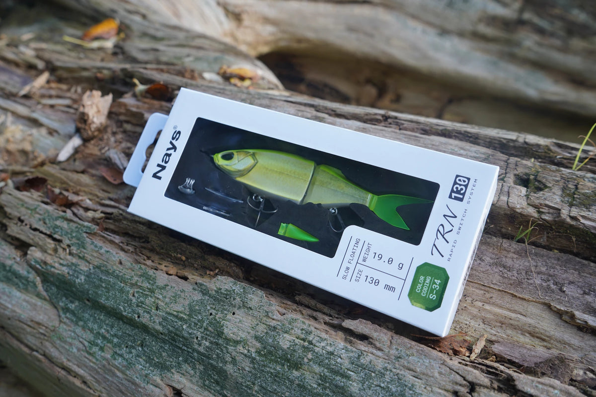 Nays TRN 130 S-34 swimbait in its box on a weathered tree log
