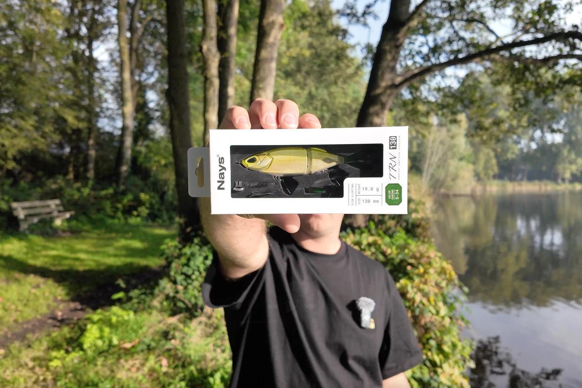 Nays TRN 130 S-34 swimbait in its box, held up by the water